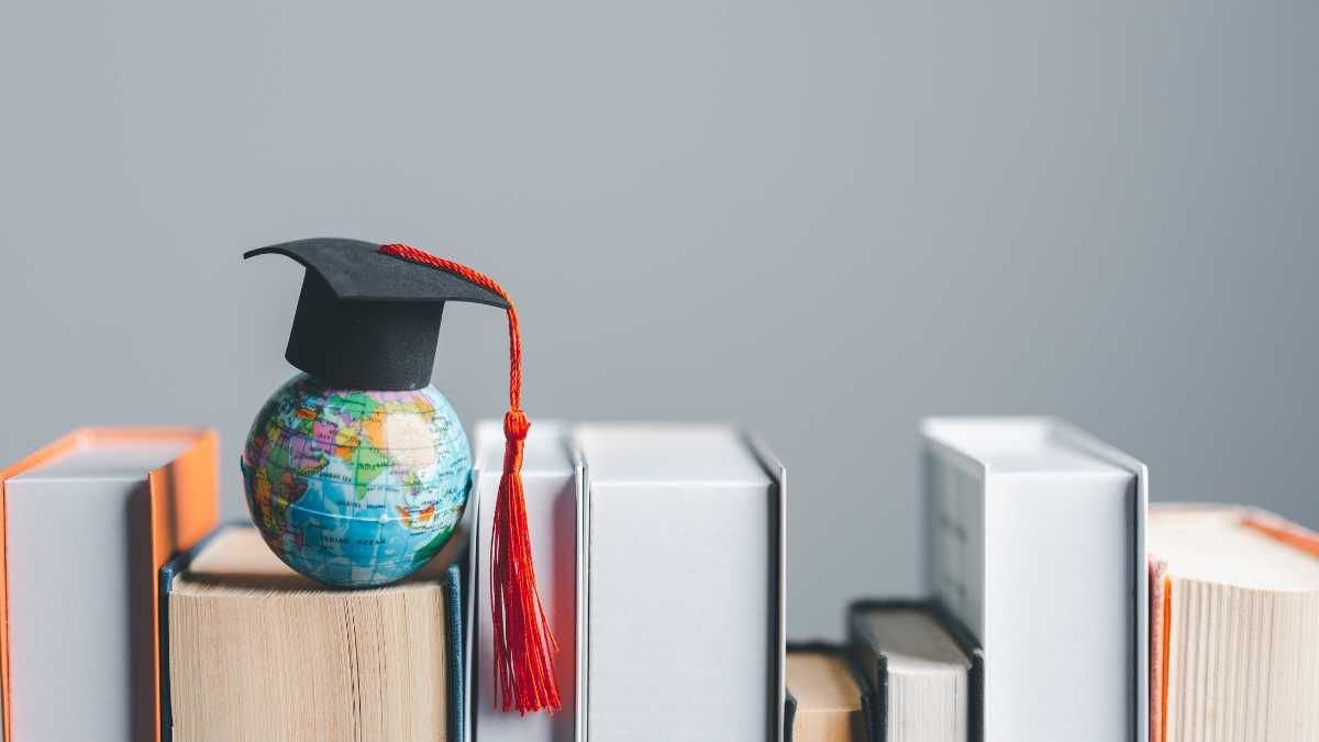 A small globe with a graduation cap on top, surrounded by books