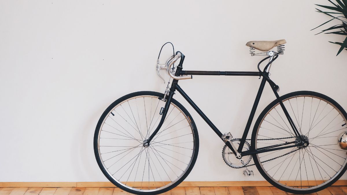 a vintage style bicycle positioned against a light-coloured wall with a wooden floor