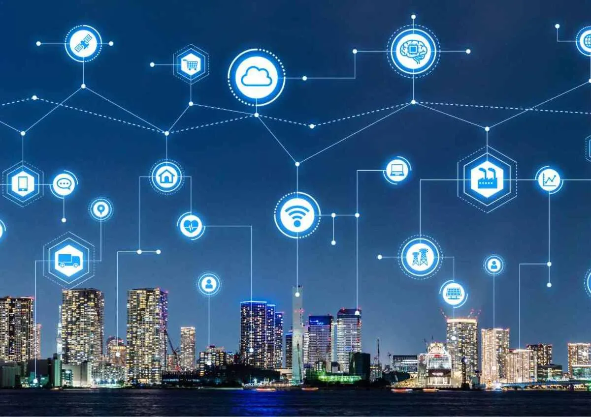 A city skyline at night with overlaying digital icons representing various connected technologies and data exchange.