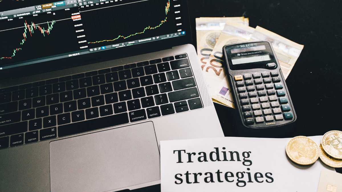 A trading setup with a laptop calculator money and Trading strategies text