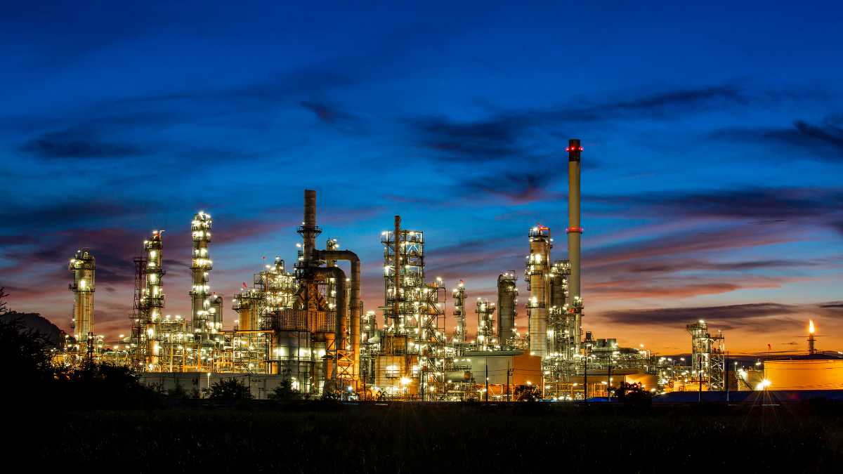 Industrial setting at twilight, showcasing a refinery or chemical plant illuminated against the evening sky