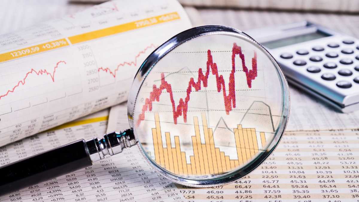 Magnifying glass on stock market graph with calculator.