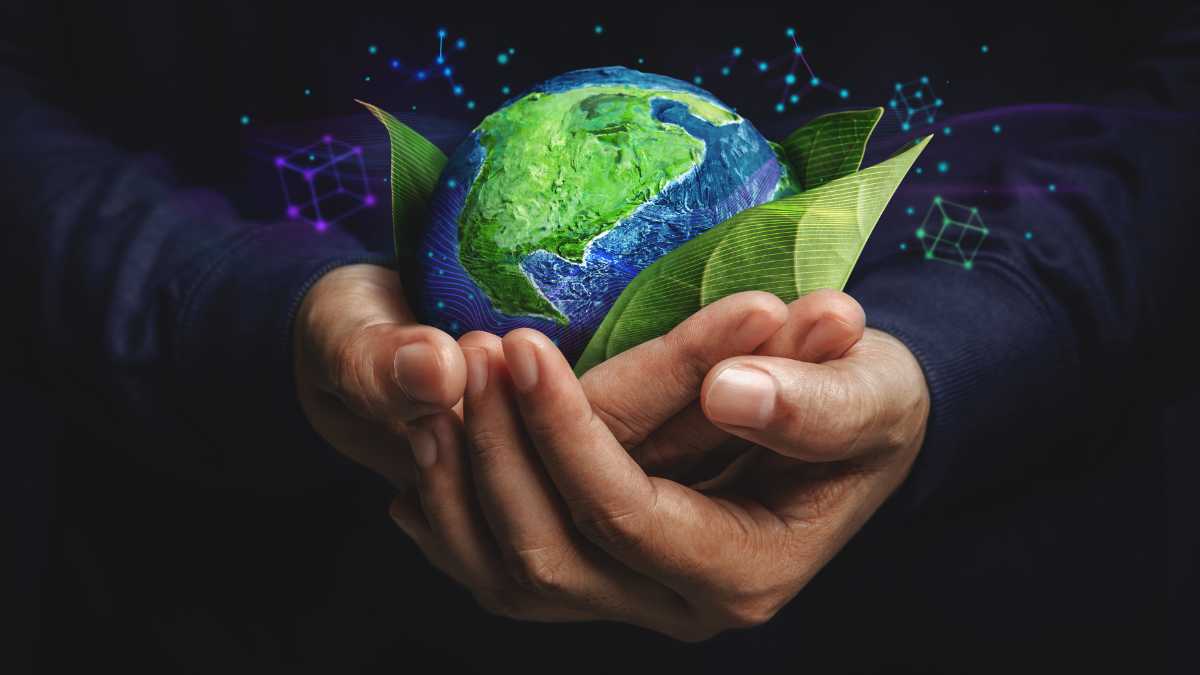 Hands cradle a vibrant Earth with green continents and blue oceans, highlighted by digital graphics and green leaves, symbolizing environmental care