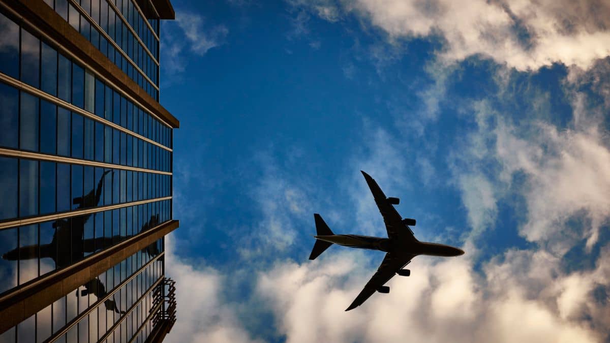 a large passenger aeroplane is silhouetted against a dramatic sky with clouds, seen from below