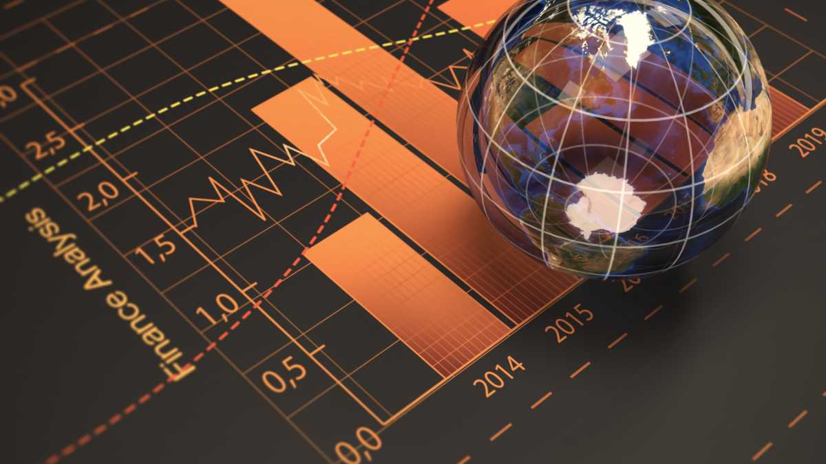 A glass globe rests on an orange financial chart symbolizing global economic trends