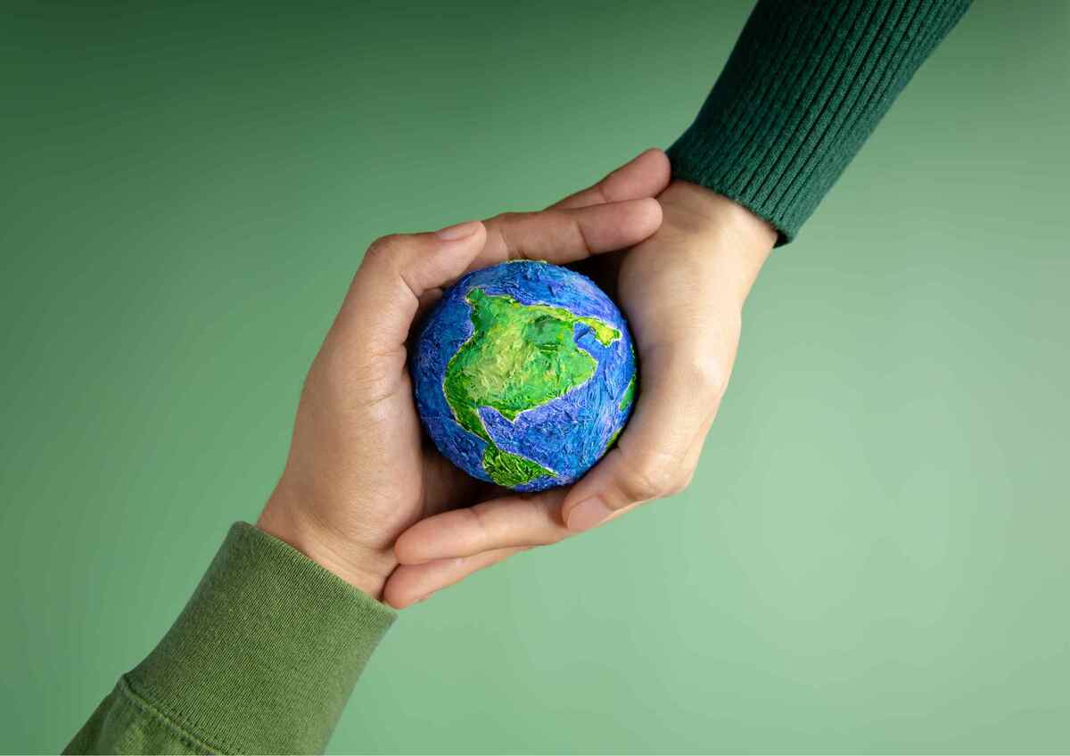 Hands holding a small, painted model of Earth, symbolizing environmental care