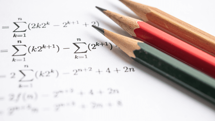 Mathematical expressions on paper with three pencils symbolising complex problem solving or academic work