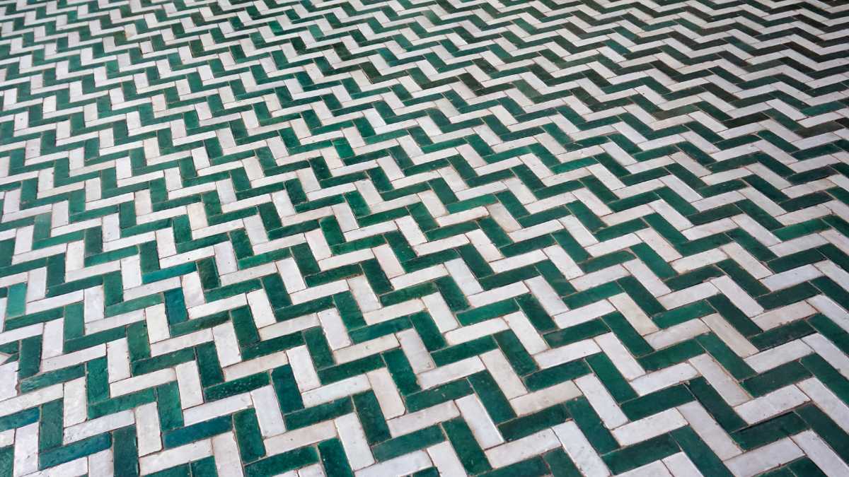 The image shows a geometric patterned floor with a three-dimensional illusion, featuring alternating white and green tiles