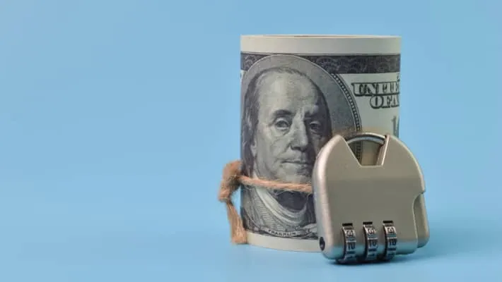 Roll of dollars secured with a padlock  on a blue background