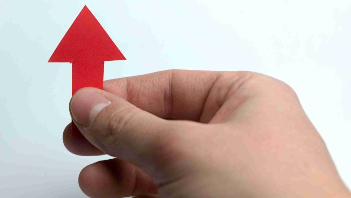 A hand holding a red arrow pointing upward