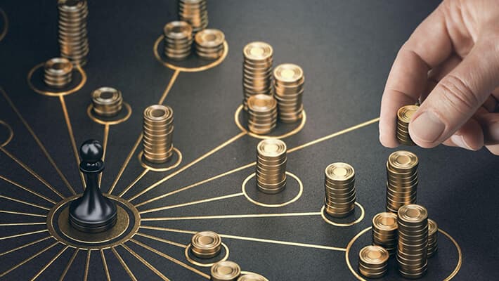 A hand stacking up coins strategically