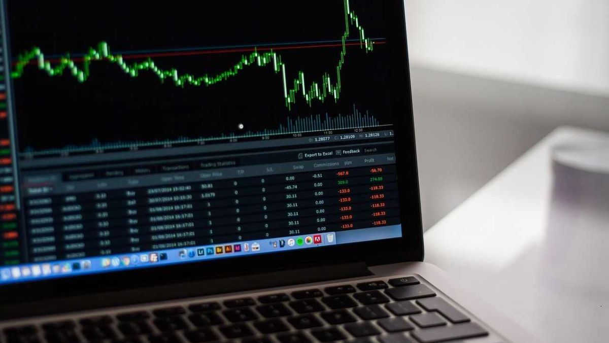 A live trading chart with green candlestick patterns displayed on a laptop