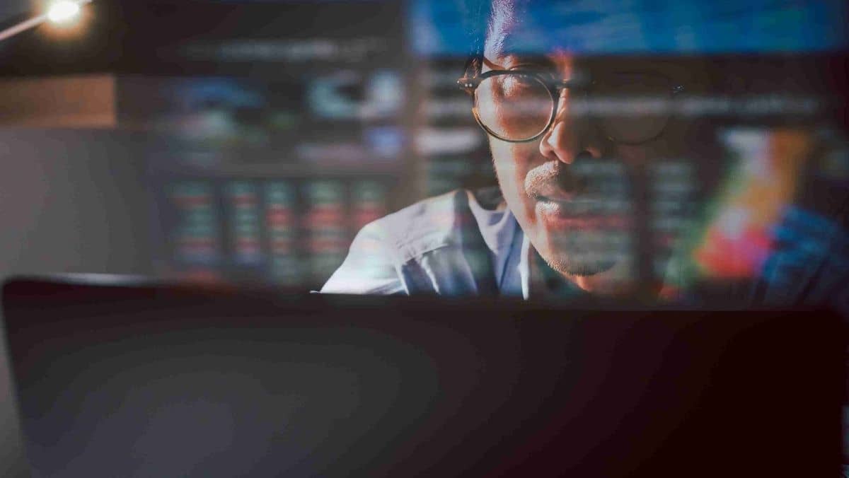 A man in eyeglasses carefully examines the content on his laptop screen