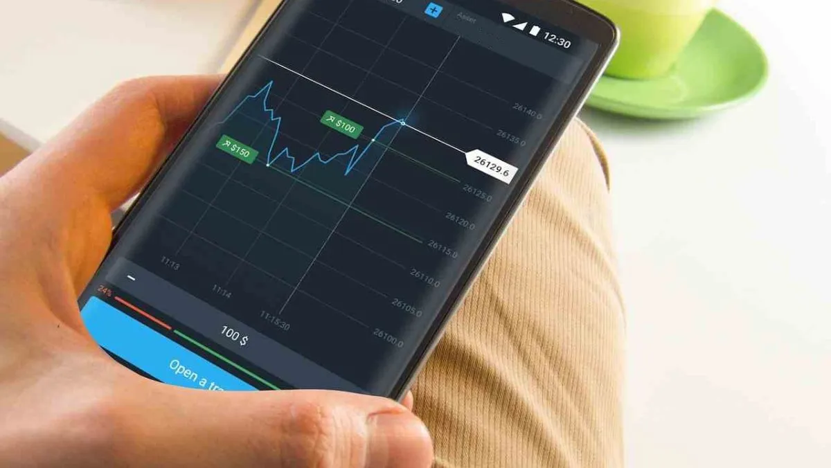 A person holding a phone displaying a trading chart