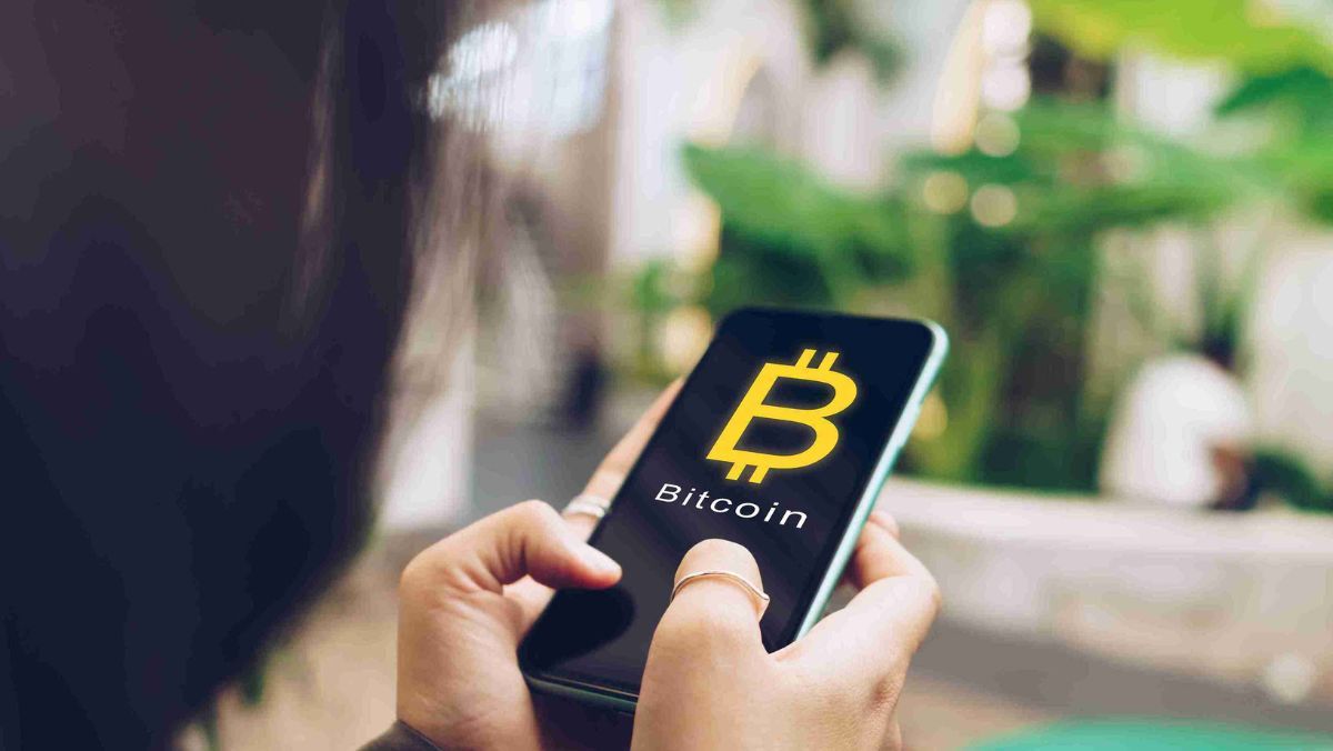 A person holding a smartphone with the recognizable Bitcoin logo