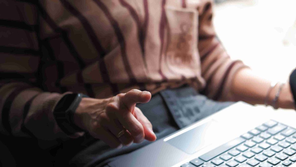 A person pointing a finger while using a laptop