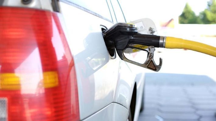 A white vehicle replenishing fuel at a gas station