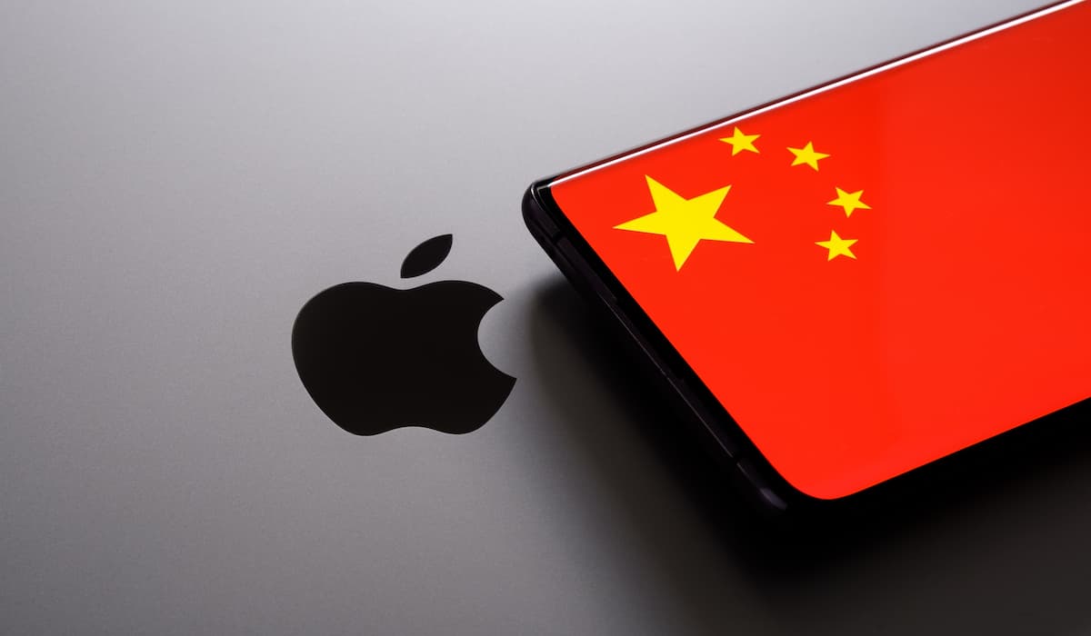 Apple stock news with Chinese flag on smartphone, highlighting market challenges.