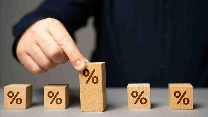 A man holding the tallest wooden block with a percentage symbol