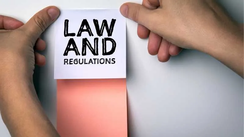 Hands pulling a tab with LAW AND REGULATIONS written on it