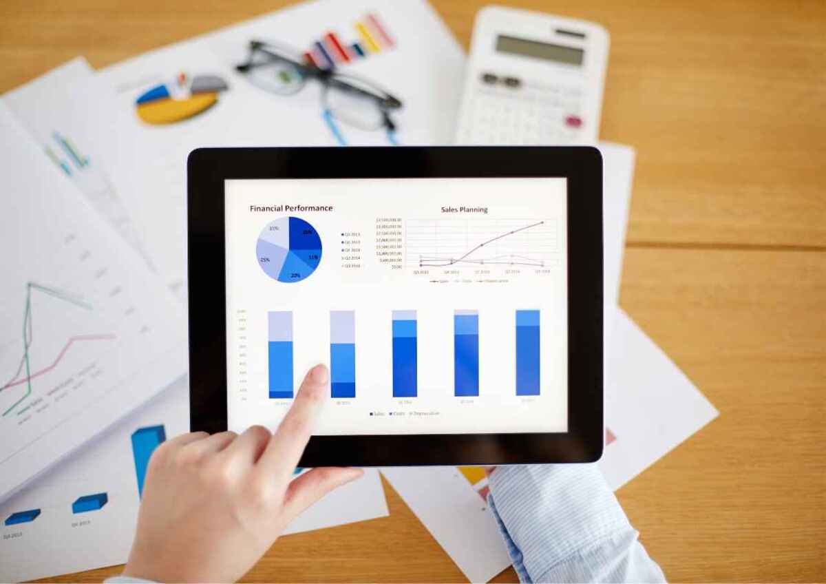 Analysing graphs on a digital tablet over paperwork.