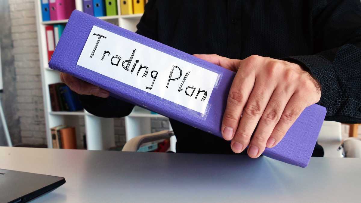 Person holding a binder labelled Trading Plan in an office setting