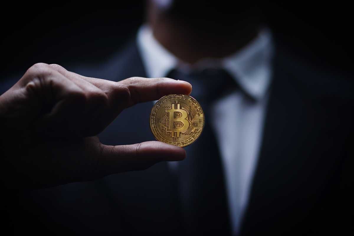 Person in suit holding a Bitcoin coin