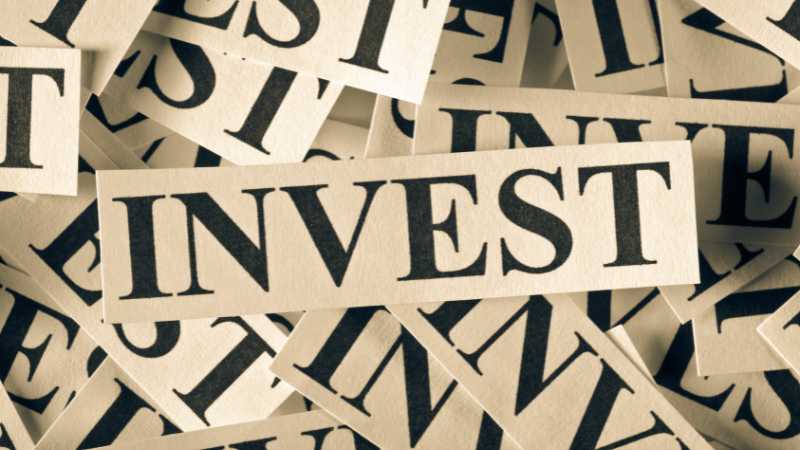 Scattered newspaper clippings with the word INVEST