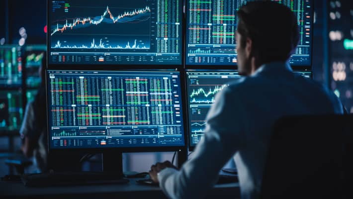 A person studying a screen with trading charts