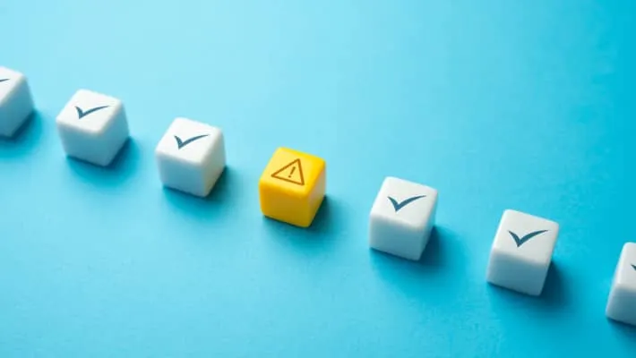 White diceblocks displaying symbols of a checkmark and a warning sign on a blue background.