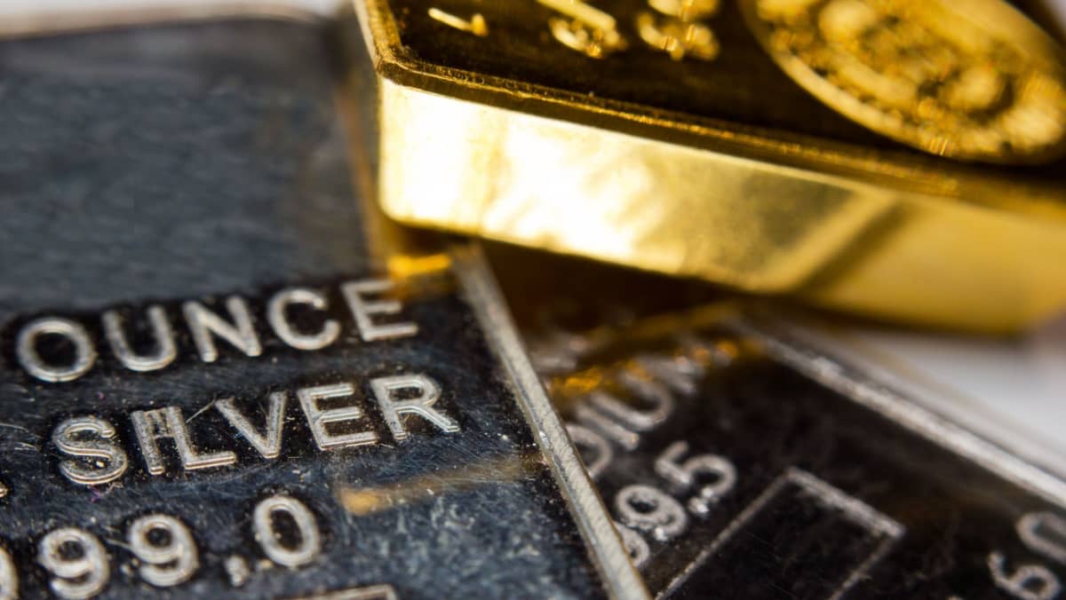 A macro shot showcasing a gold ingot placed on top of a troy ounce silver and palladium bar