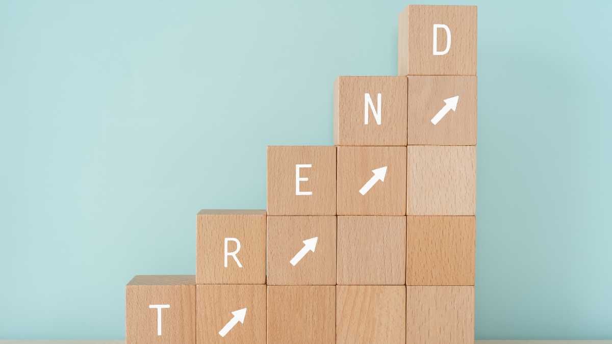 Wooden blocks with letters TREND and upward arrows on a blue background