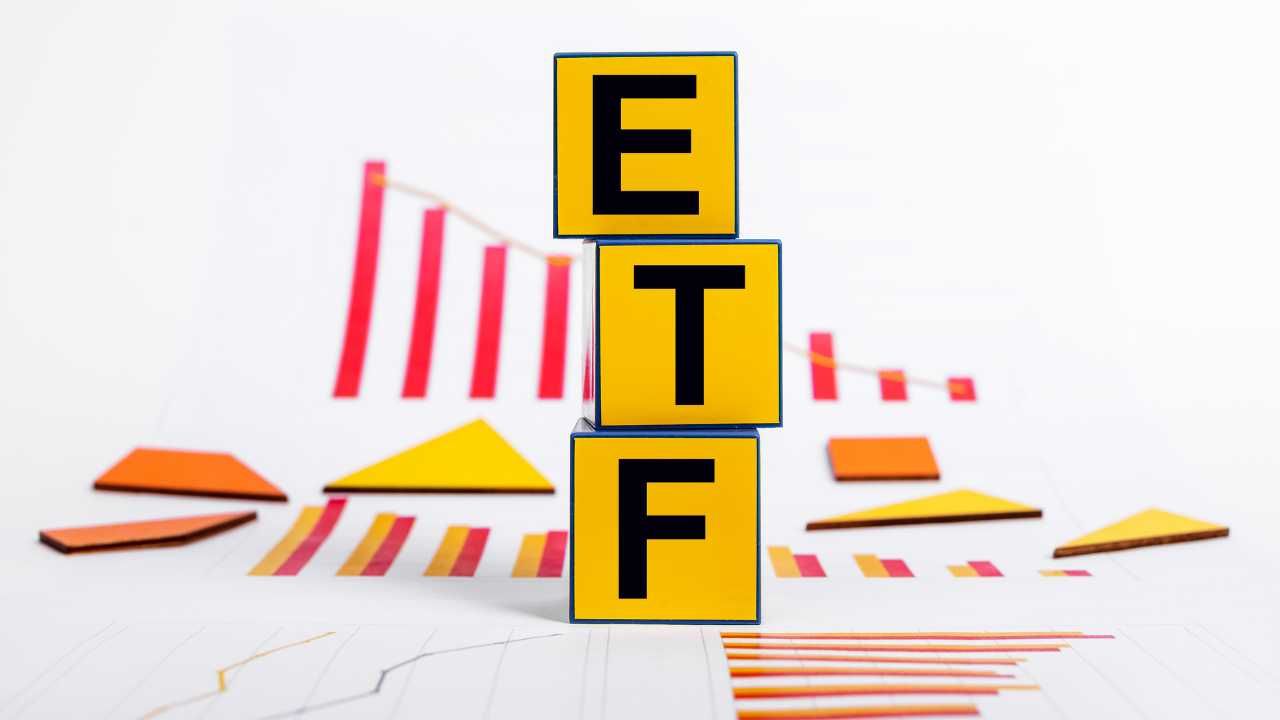 Yellow blocks spelling  ETF  with finance charts in the background