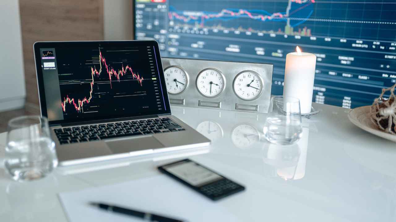 A laptop on a table with clocks and a candle