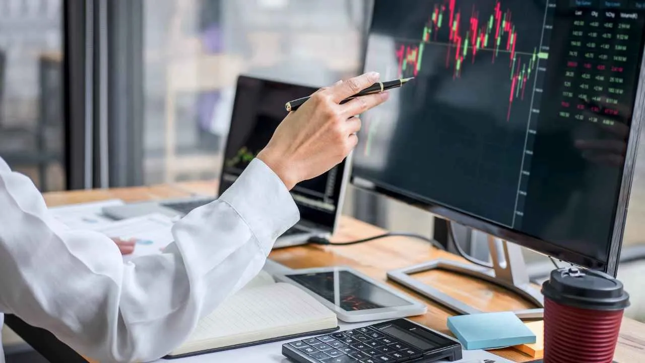 a person holding a pen at a computer screen