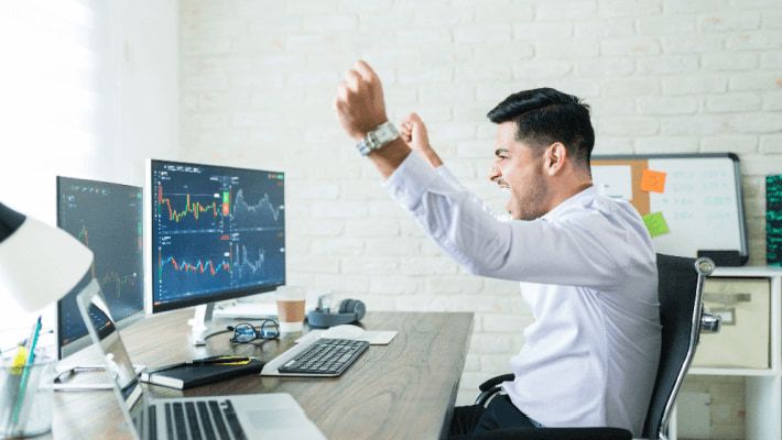 Joyful man with glasses celebrates at the trading desk