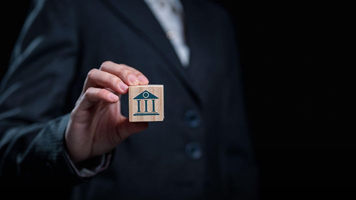 a person holding a wooden block with an icon symbolising a financial bank