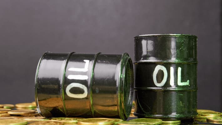 Two oil barrels in black resting atop a scattered pile of golden coins