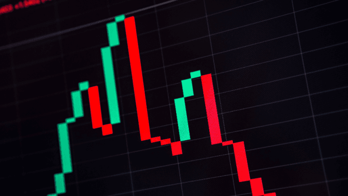 Close-up of a financial graph showing red and green candlestick patterns on a dark background