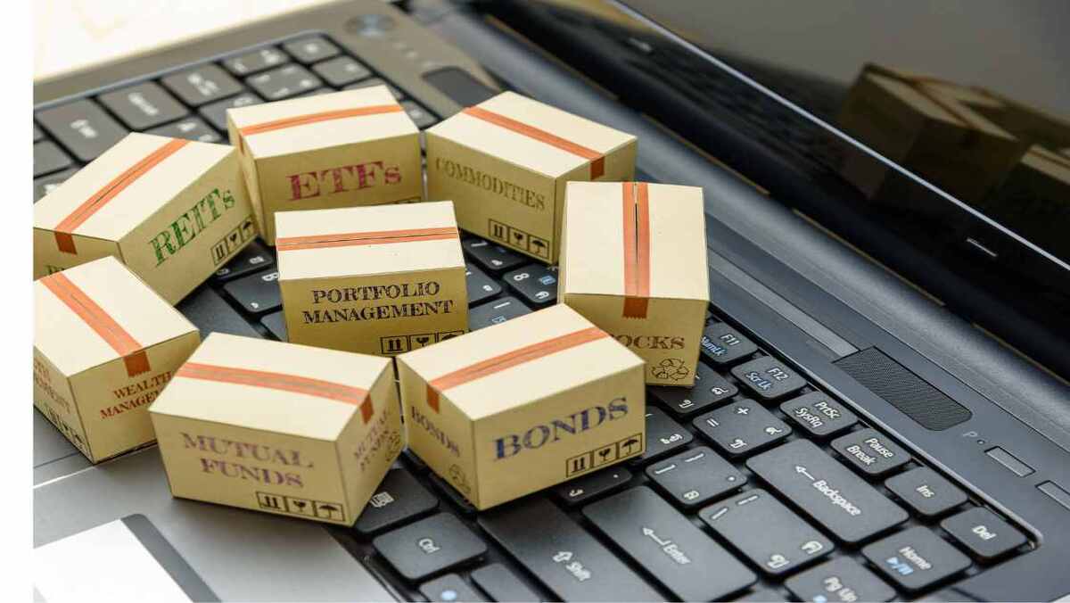 Cardboard boxes labelled with various investment types on a laptop keyboard.