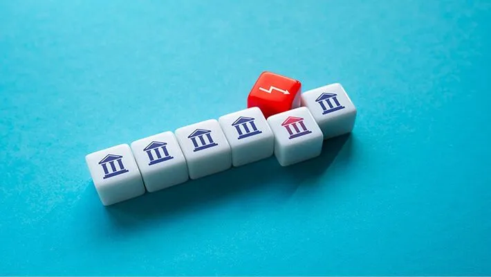 White dice with blue bank icons lined up, one red die with a white arrow on a turquoise background.